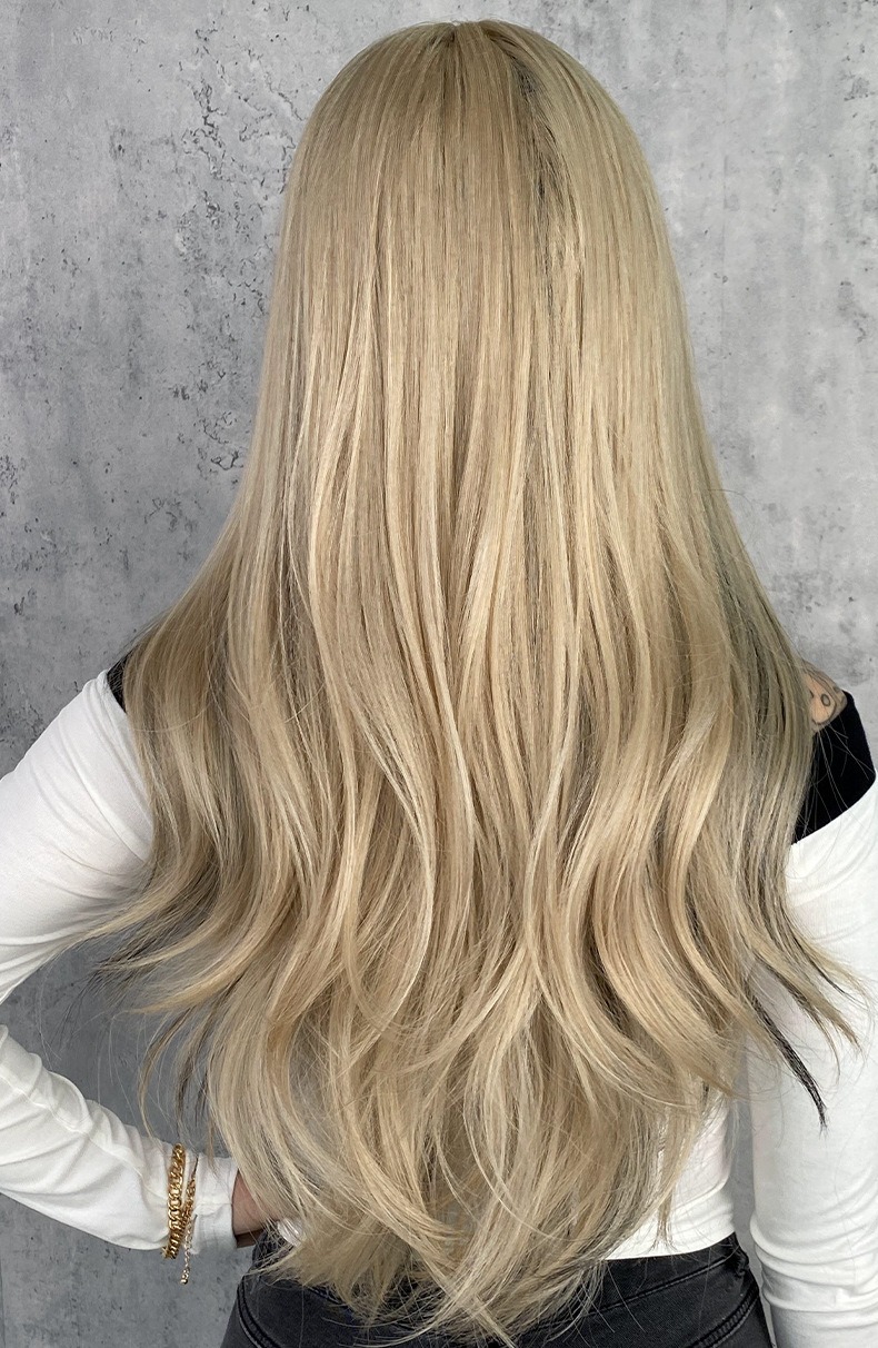 A synthetic wig with long curly blonde hair, bangs, and highlights dyed into large waves